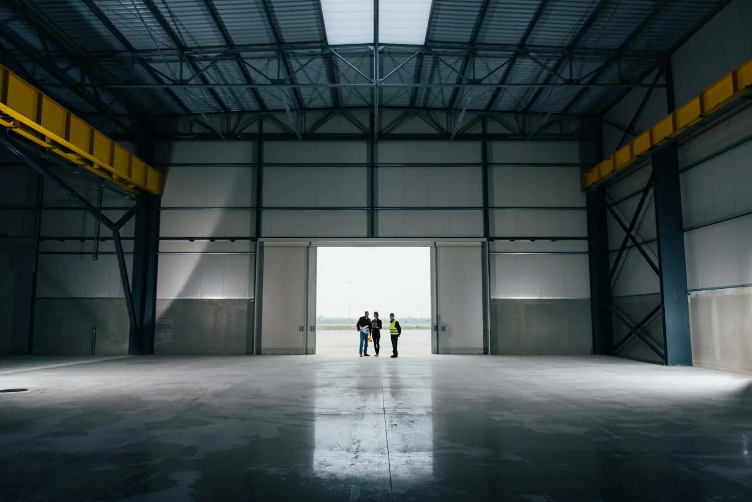 Equipe de arquitetos e chefe de obras analisando um galpão industrial